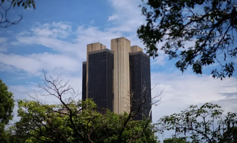 A discussão sobre política monetária do país tem como pano de fundo a fotografia da sede do Banco Central em Brasília. A decisão do BC manter taxas de juro elevadas por um longo período é confirmada pela ata do CMN, refletindo a preocupação com a inflação e estabilidade financeira, embora possa ter consequências negativas para a economia em curto prazo.