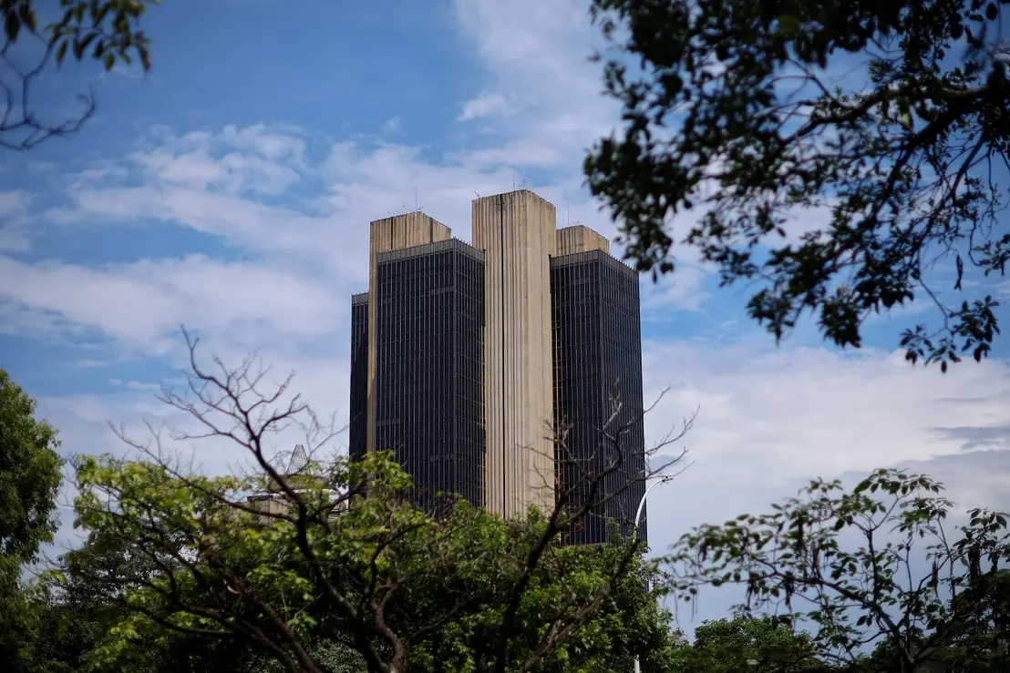 A discussão sobre política monetária do país tem como pano de fundo a fotografia da sede do Banco Central em Brasília. A decisão do BC manter taxas de juro elevadas por um longo período é confirmada pela ata do CMN, refletindo a preocupação com a inflação e estabilidade financeira, embora possa ter consequências negativas para a economia em curto prazo.