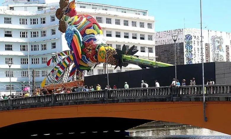 A escultura do Galo Folião Fraterno, localizada na Ponte Duarte Coelho, é um tributo ao legado de Dom Helder Câmara e Nise da Silveira, com materiais reciclados e arte 3D.