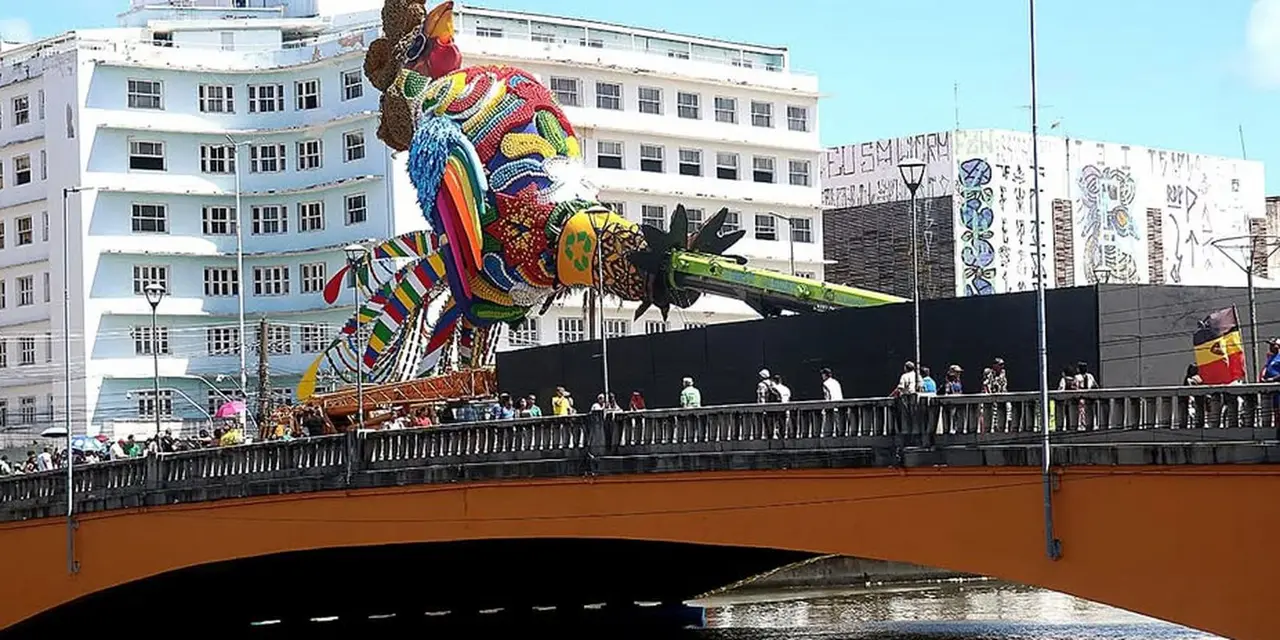 A escultura do Galo Folião Fraterno, localizada na Ponte Duarte Coelho, é um tributo ao legado de Dom Helder Câmara e Nise da Silveira, com materiais reciclados e arte 3D.